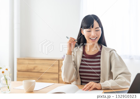 リモート授業を受けてノートをとっている若い女性 リモート授業を受けてノートをとっている若い女性 132910323