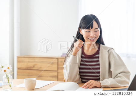 リモート授業を受けてノートをとっている若い女性 リモート授業を受けてノートをとっている若い女性 132910324