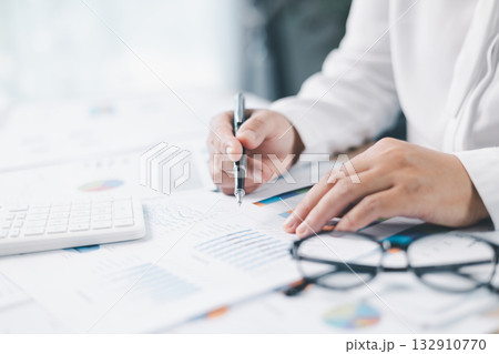 Businessman reviews financial reports, points on chart with pen while analyzing data at office desk working with calculator for accuracy. Concept of accounting, business planning, investment strategy. 132910770