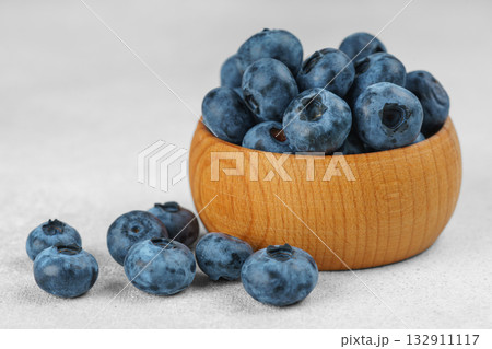 Fresh ripe blueberries in wooden bowl on light gray stone background closeup macro healthy food Fresh ripe blueberries in wooden bowl on light gray stone background closeup macro healthy food 132911117