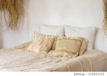 Soft beige pillows, decorative cushions on cozy bed with natural linen textile in bright sunlight Soft beige pillows, decorative cushions on cozy bed with natural linen textile in bright sunlight 132911132