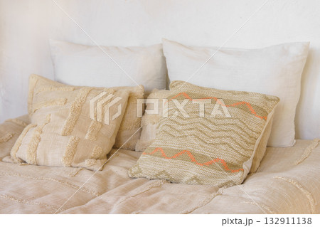 Soft beige pillows, decorative cushions on cozy bed with natural linen textile in bright sunlight Soft beige pillows, decorative cushions on cozy bed with natural linen textile in bright sunlight 132911138