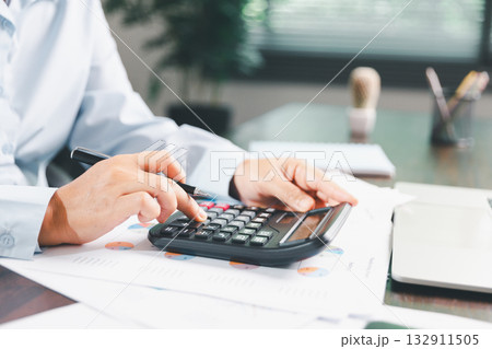 Businesswoman manages finances by using banking and accounting system to calculate costs, taxes, investments, illustrating a business, finance, and real estate concept focused on financial strategy. Businesswoman manages finances by using banking and accounting system to calculate costs, taxes, investments, illustrating a business, finance, and real estate concept focused on financial strategy. 132911505