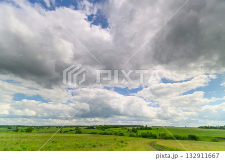A Vast, Expansive Green Landscape Set Against a Dramatic and Cloudy Sky Above It 132911667
