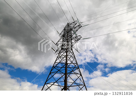 A tall electricity transmission tower stands under a dramatic gray and white cloudy sky 132911816