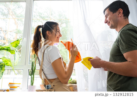 Husband helps his wife manually washes window of house with rag cleaner and mop inside interior. Restoring order and cleanliness, cleaning servise Husband helps his wife manually washes window of house with rag cleaner and mop inside interior. Restoring order and cleanliness, cleaning servise 132912815