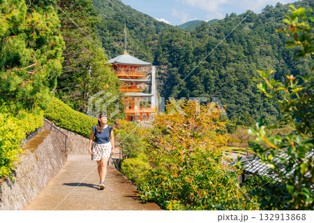 Smiling woman explores Nachi Falls and Seigantoji Temple, a beautiful Japanese cultural site Smiling woman explores Nachi Falls and Seigantoji Temple, a beautiful Japanese cultural site 132913868