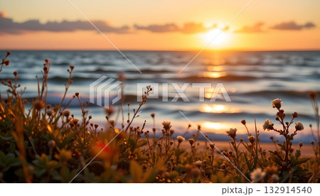 A serene coastal sunset scene, with the warm glow of the sun setting behind the horizon line 132914540