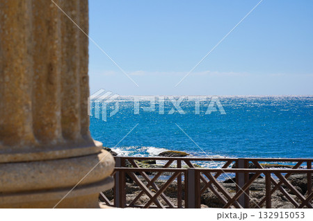 A Serene Coastal View Featuring Crystal-Clear Blue Waters, Rocky Shoreline, and Elegant Architectural Details in the Foreground A Serene Coastal View Featuring Crystal-Clear Blue Waters, Rocky Shoreline, and Elegant Architectural Details in the Foreground 132915053