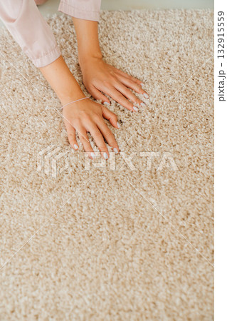 a woman's hand touching the beige Interior pile carpet made of polypropylene. a woman's hand touching the beige Interior pile carpet made of polypropylene. 132915559