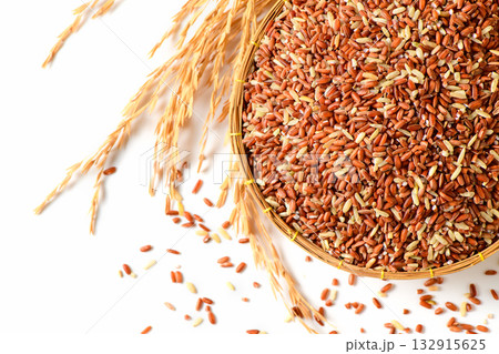 Close up of organic brown rice grains in a bamboo basket with golden rice stalks on a white background. Close up of organic brown rice grains in a bamboo basket with golden rice stalks on a white background. 132915625