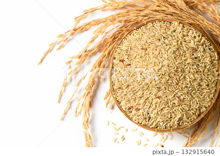 top view of traditional woven basket filled with uncooked brown rice grains isolated. 132915640