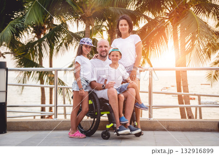 Disabled man in a wheelchair with his family on the beach. 132916899