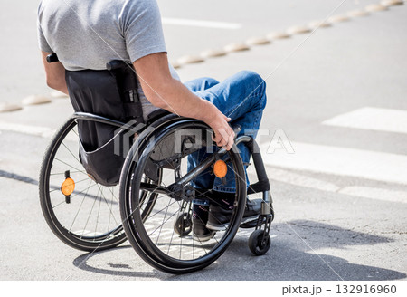 Handicapped man in wheelchair preparing to cross the road on pedestrian crossing 132916960