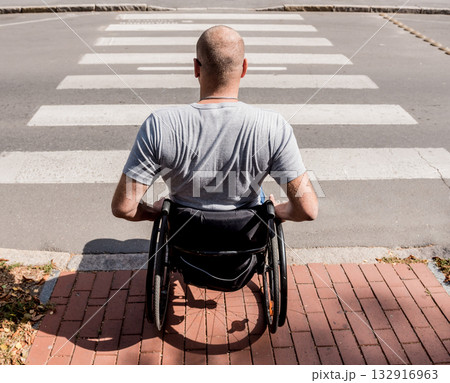 Handicapped man in wheelchair preparing to cross the road on pedestrian crossing 132916963