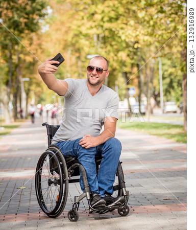 Handicapped man in wheelchair at the park alley use a smartphone 132916989