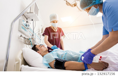 Doctors give resuscitation to a male patient in the emergency room. 132917156