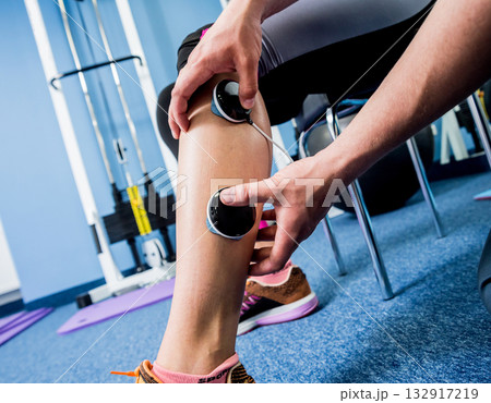 Physical therapist install electrostimulator on the muscles of the legs. Physical therapist install electrostimulator on the muscles of the legs. 132917219