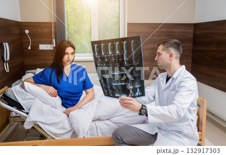 Traumatologist showing MRI film to patient in hospital. 132917303
