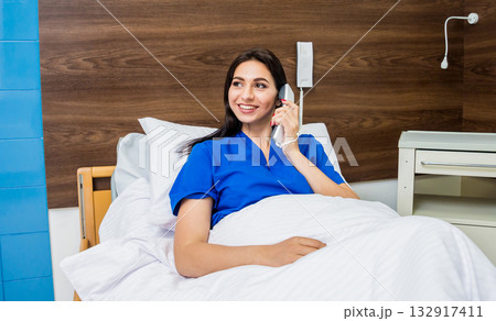 Patient talking on the phone in hospital bed. Young caucasian woman. 132917411