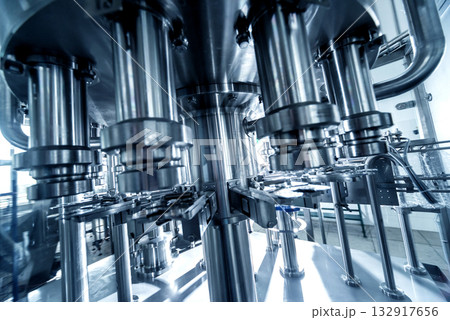 Automatic filling machine pours water into plastic PET bottles. 132917656