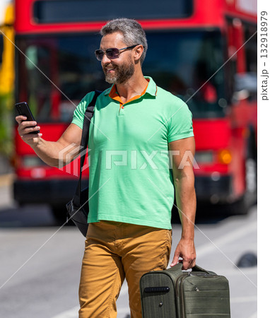 Hispanic tourist traveler book online outdoor. Tourist with travel bag. Traveler using phone. Tourist booking vacation trip. Traveler suitcase for summer trip. Man booking summer trip. Video call 132918979