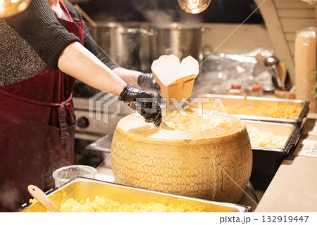 Italian pasta served in a cheese head, a street food item, is served in the city center at the Christmas market in Krakow, Poland. Italian pasta served in a cheese head, a street food item, is served in the city center at the Christmas market in Krakow, Poland. 132919447