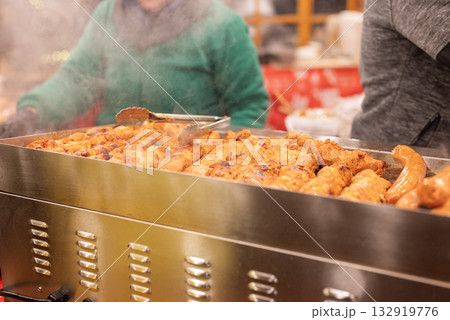 vendor fries meat and sausage on the grill in the city center at the Christmas market in Gdansk Poland vendor fries meat and sausage on the grill in the city center at the Christmas market in Gdansk Poland 132919776