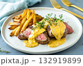 Closeup of grilled steak with French fries and creamy mustard sauce on a ceramic plate. High-protein restaurant-style dish, perfect for advertising lunch menus, takeout, or food delivery services 132919899