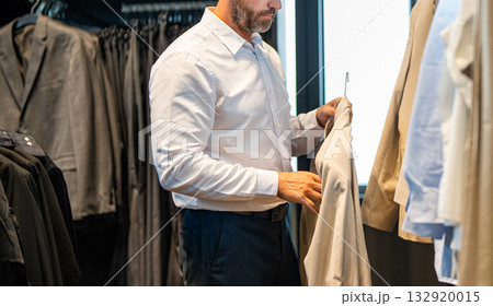 Trendy suit jacket. Hispanic businessman choosing tailoring. Bespoke tailoring. Male model in suit boutique. Retail assistant help stylish man to find suit. Stylish man in suit, cropped view 132920015