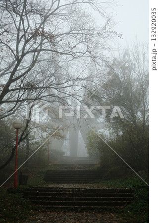 Mysterious view of the Kosmaj Monument rising through dense fog, surrounded by autumn trees and quiet forest atmosphere Mysterious view of the Kosmaj Monument rising through dense fog, surrounded by autumn trees and quiet forest atmosphere 132920035