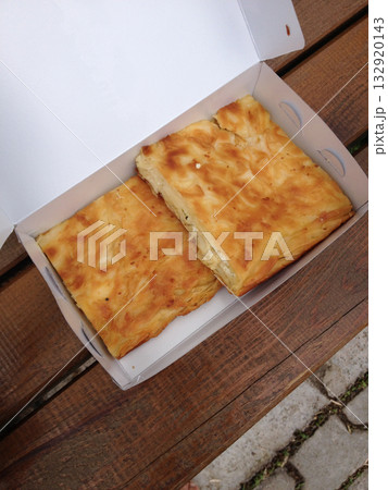 Traditional Turkish pastry in a takeaway box on wooden bench. Comfort, simplicity, culture, warmth, and the joy of street food shared in everyday life. 132920143