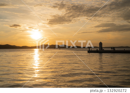 A beautiful sunset on the seafront promenade with a lighthouse landmark in Zadar, Croatia. 132920272