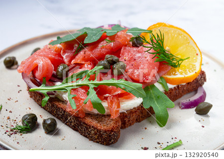 sandwich with freshly smoked salmon, on black bread, with cottage cheese, with herbs and red onions, capers and pieces of citrus fruits, on a marble countertop, breakfast, no people, sandwich with freshly smoked salmon, on black bread, with cottage cheese, with herbs and red onions, capers and pieces of citrus fruits, on a marble countertop, breakfast, no people, 132920540