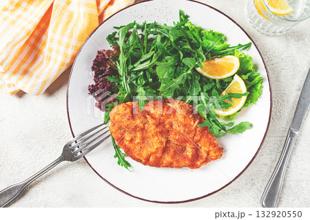 Milanese chicken, Crispy breaded chicken served, with fresh herbs, and lemon wedges, 132920550