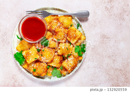 fried ravioli with parmesan cheese, served with red sauce and garnished with herbs, on a light background, no people, fried ravioli with parmesan cheese, served with red sauce and garnished with herbs, on a light background, no people, 132920559