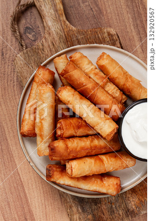 fried spring rolls with cheese, on a wooden background, with cream sauce, no people, 132920567