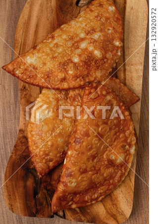 Fried chebureks, close-up, on a wooden chopping board, no people Fried chebureks, close-up, on a wooden chopping board, no people 132920572