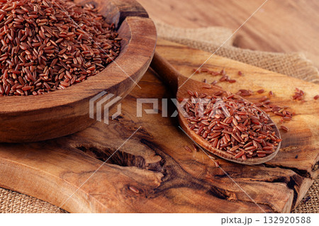 Natural red rice, in a wooden bowl and spoon on a wooden surface in rustic style, top view Natural red rice, in a wooden bowl and spoon on a wooden surface in rustic style, top view 132920588