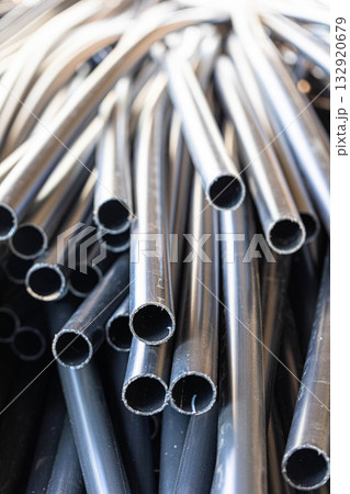 Black plastic pipes stacked together in a chaotic arrangement 132920679