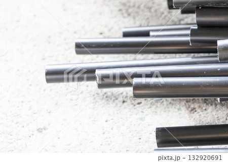 Stacked black plastic pipes on concrete surface with industrial texture 132920691
