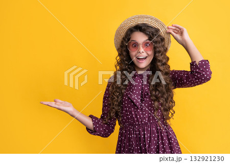 surprised happy child in straw hat and sunglasses with long brunette curly hair. copy space 132921230