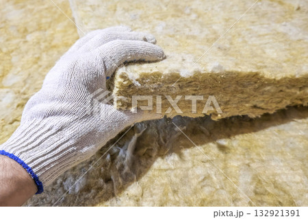 Close up a gloved hand takes a sheet of thermal insulation material. Close up a gloved hand takes a sheet of thermal insulation material. 132921391