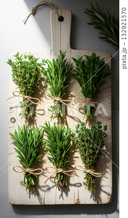 Six Bundles of Fresh Thyme and Rosemary Herbs Tied with Twine on a Rustic Cutting Board, Highlighted by Moody Sunlight. 132921570