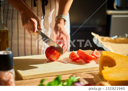 Woman cutting tomato on wooden board in kitchen 132921940