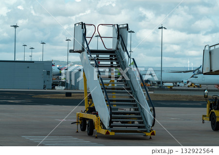 Airport boarding stairs on tarmac with airplanes in background Airport boarding stairs on tarmac with airplanes in background 132922564