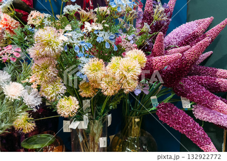 Assorted artificial flower bouquets displayed in glass vases. Greenwashing, consumer overproduction, microplastics, environmental awareness Assorted artificial flower bouquets displayed in glass vases. Greenwashing, consumer overproduction, microplastics, environmental awareness 132922772