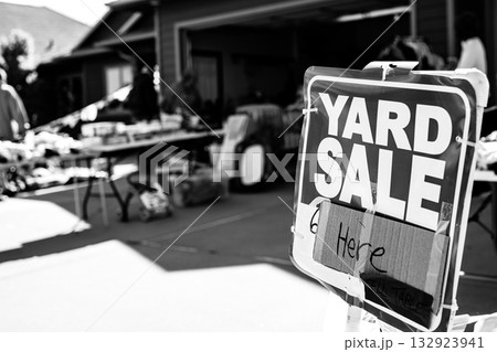 Selective focus on a yard sale sign with blurred tables of material  132923941