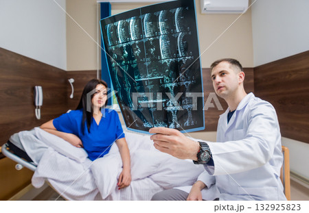 Traumatologist showing MRI film to patient in hospital. 132925823