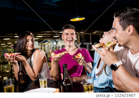 Cheerful friends in the pub. Drinking beer, eating pizza, talking, having fun. Cheerful friends in the pub. Drinking beer, eating pizza, talking, having fun. 132925907